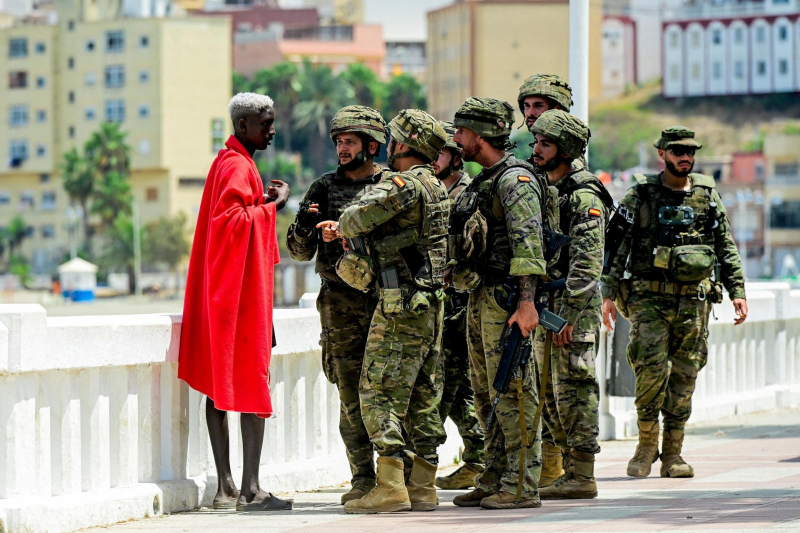 Испанские военнослужащие опрашивают мигранта в Сеуте после массового перехода границы